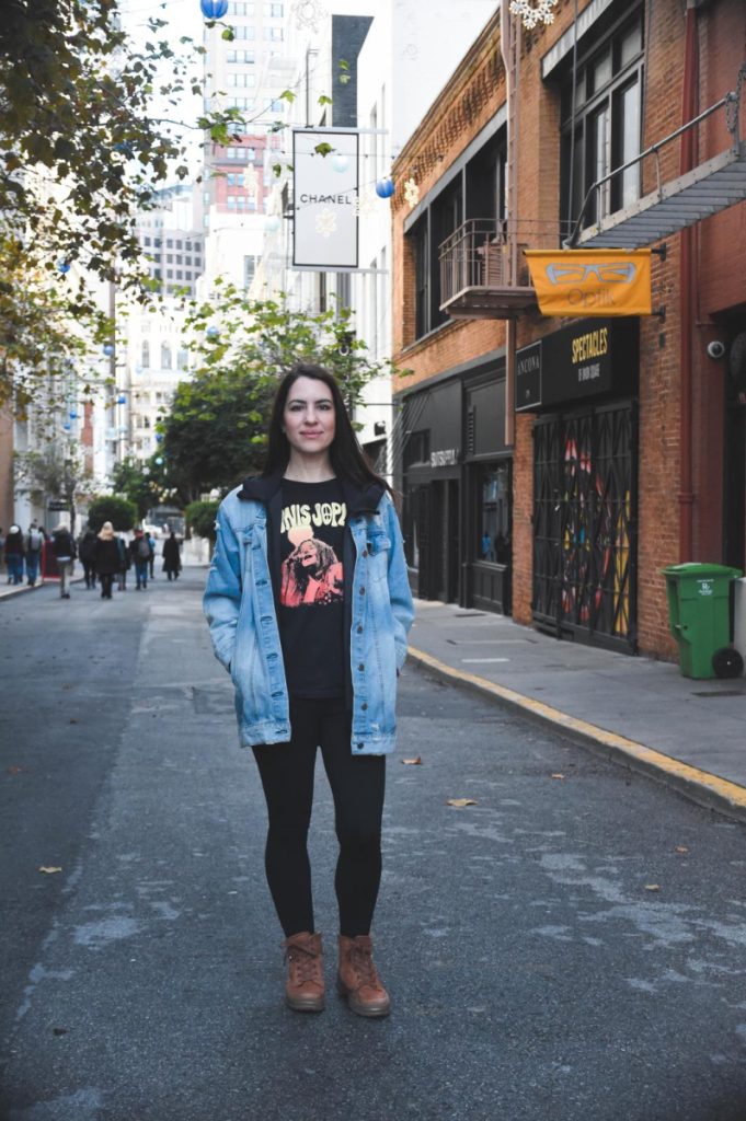 Helen standing and smiling, wearing a blue denim jacket.